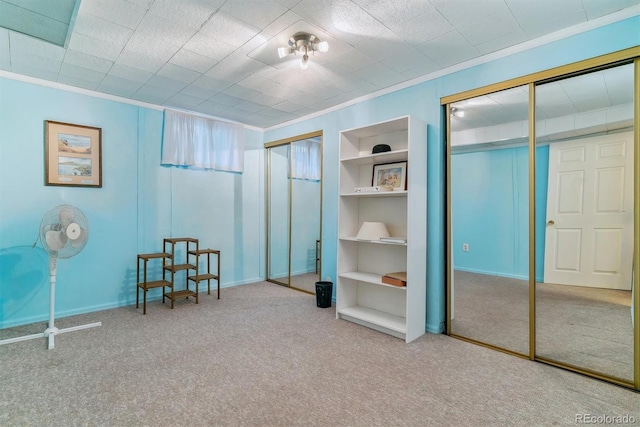 carpeted bedroom with baseboards, two closets, and ornamental molding