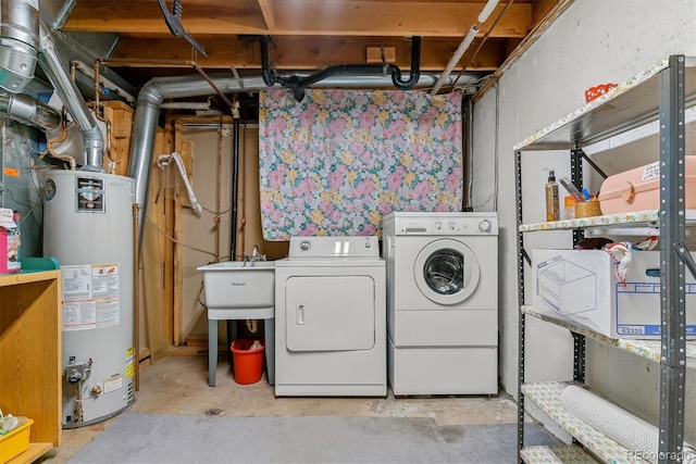 clothes washing area with laundry area, separate washer and dryer, water heater, and a sink