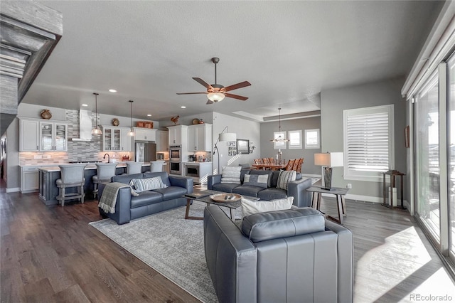 living room featuring a textured ceiling, ceiling fan, and dark wood-type flooring