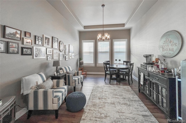 living room with a raised ceiling, dark hardwood / wood-style flooring, and a notable chandelier