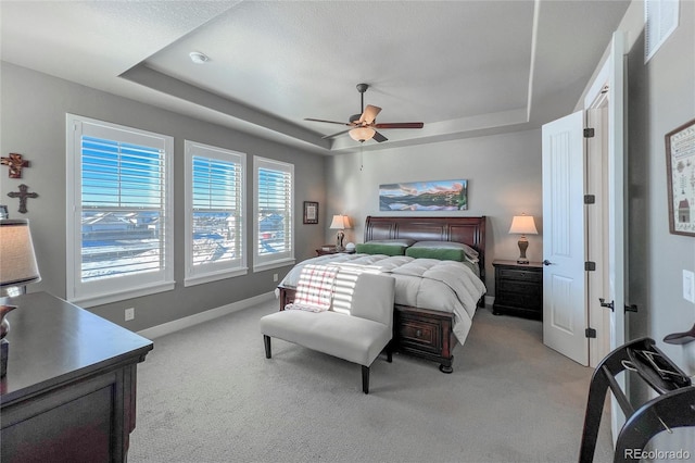 bedroom featuring light carpet, a raised ceiling, and ceiling fan