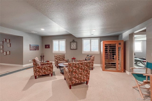 living area featuring a healthy amount of sunlight, light colored carpet, and a textured ceiling