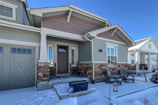 snow covered property entrance featuring a garage