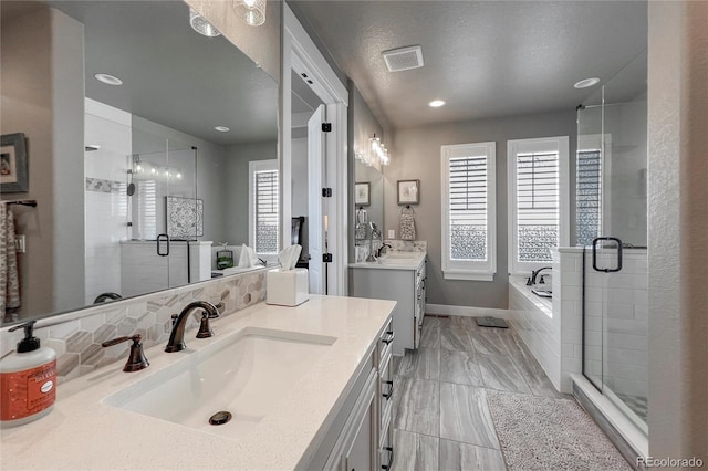 bathroom with plus walk in shower, vanity, a textured ceiling, and a wealth of natural light