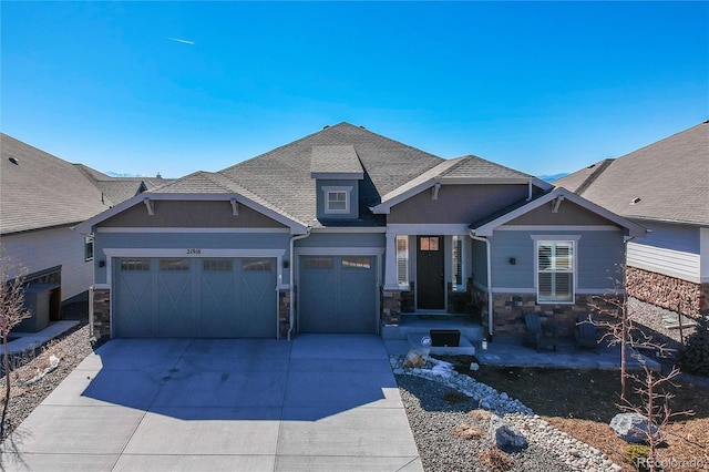 craftsman house featuring driveway, stone siding, an attached garage, and a shingled roof