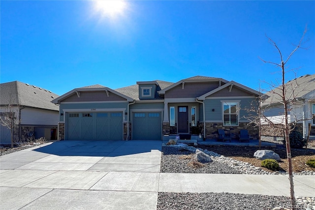 craftsman-style house featuring an attached garage, stone siding, and concrete driveway