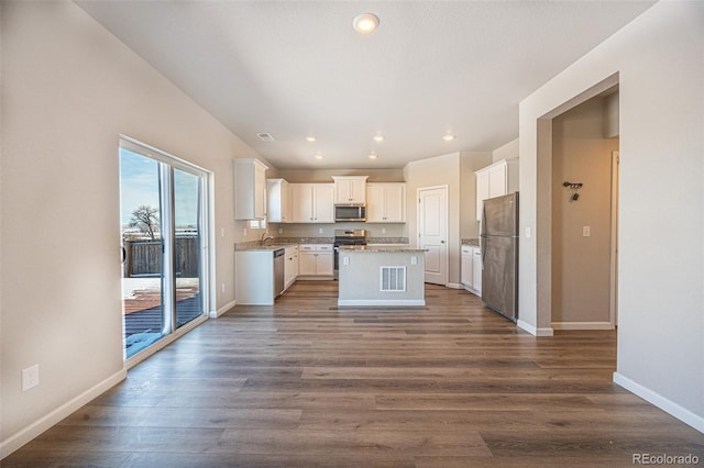 kitchen with sink, dark wood-type flooring, white cabinetry, stainless steel appliances, and a center island