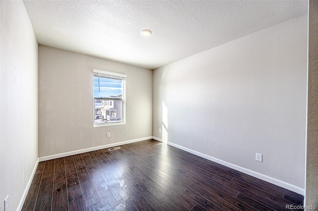 spare room with dark wood-type flooring and a textured ceiling