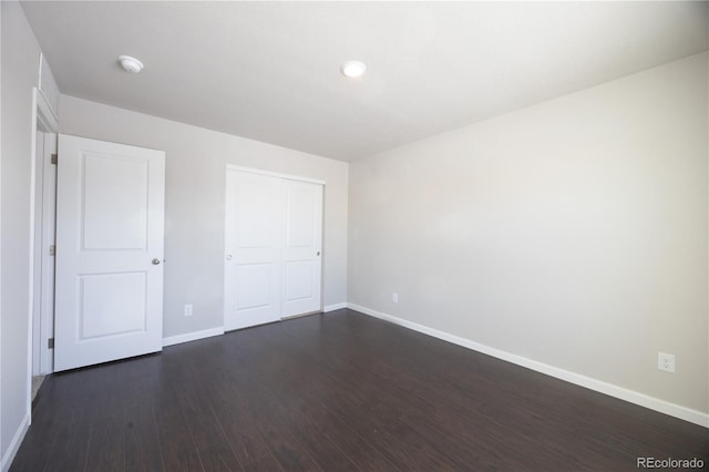 unfurnished bedroom featuring dark wood-type flooring and a closet