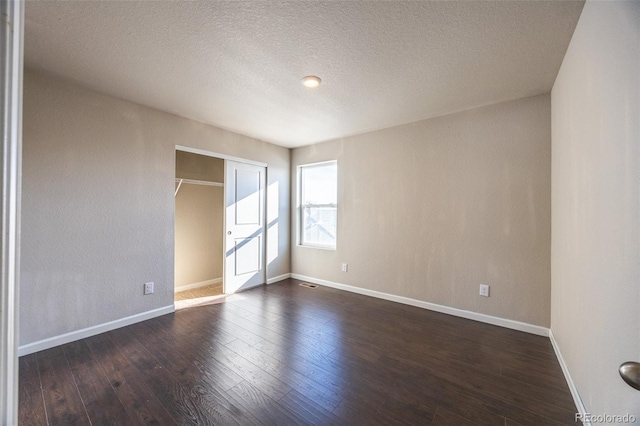 empty room featuring dark wood-type flooring and a textured ceiling