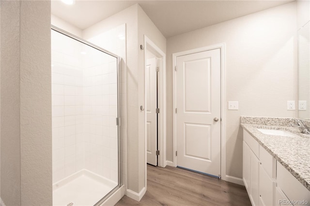 bathroom featuring hardwood / wood-style flooring, vanity, and a shower with shower door