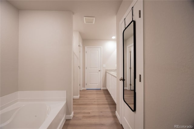 bathroom with vanity, a tub to relax in, and wood-type flooring