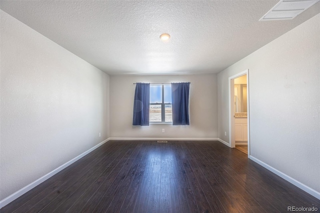 unfurnished room with dark hardwood / wood-style flooring and a textured ceiling