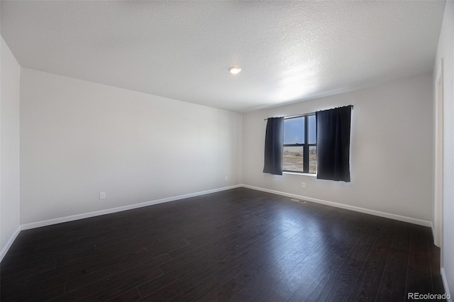 spare room with dark hardwood / wood-style floors and a textured ceiling