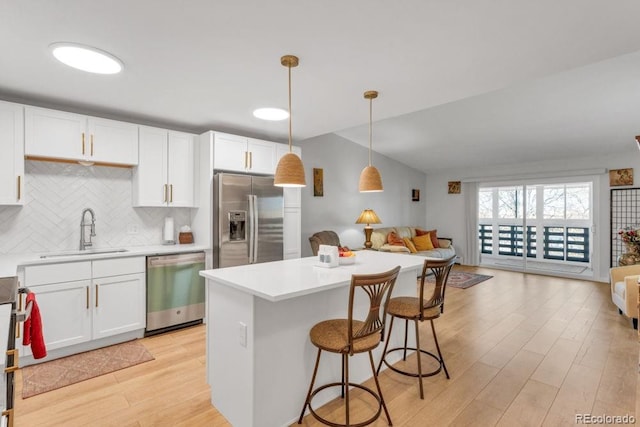 kitchen with pendant lighting, appliances with stainless steel finishes, white cabinetry, tasteful backsplash, and sink