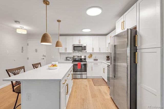 kitchen with pendant lighting, stainless steel appliances, a breakfast bar area, and white cabinets