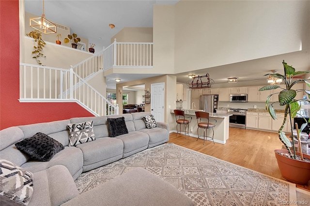 106 Cherry St, Castle Rock, CO 80104 - living room featuring a towering ceiling, stairway, light wood-style floors, and a chandelier