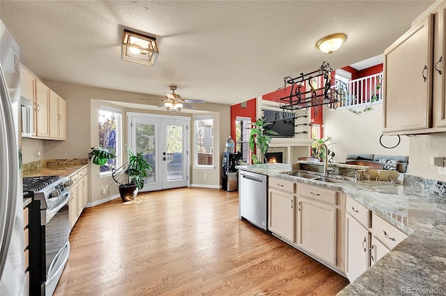 106 Cherry St, Castle Rock, CO 80104 - kitchen with stainless steel appliances, a lit fireplace, a peninsula, light wood-style flooring, and a textured ceiling