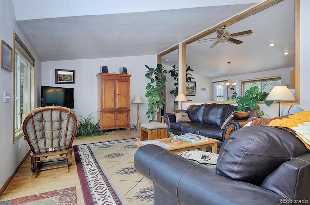 living room with lofted ceiling, ceiling fan with notable chandelier, and light wood-type flooring