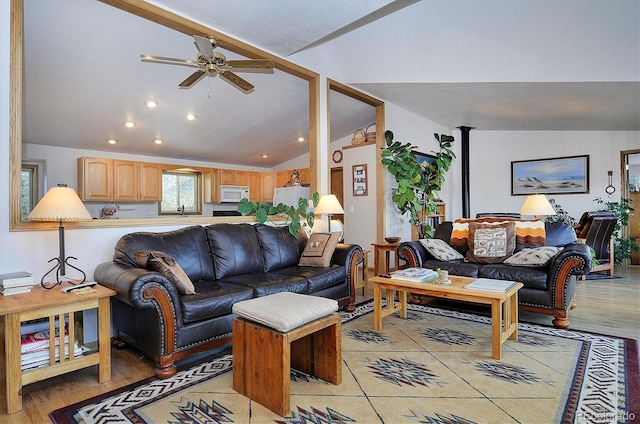 living room featuring ceiling fan, vaulted ceiling, and light wood-type flooring