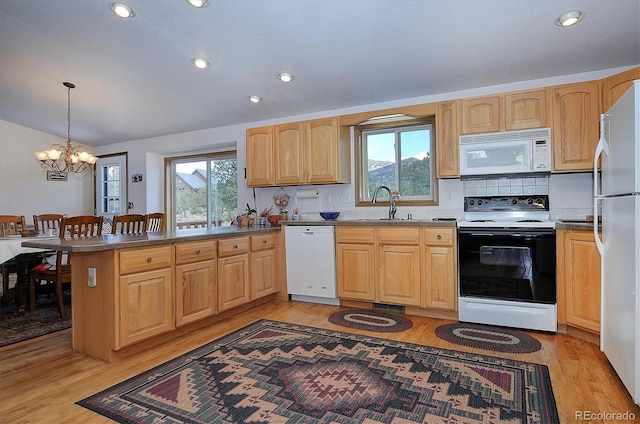 kitchen with pendant lighting, sink, white appliances, kitchen peninsula, and light wood-type flooring