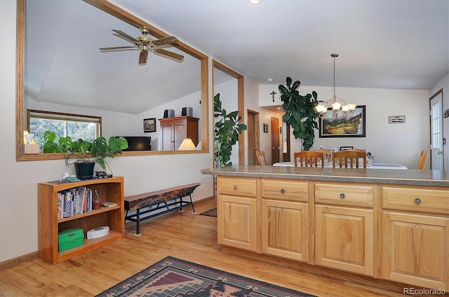 kitchen featuring lofted ceiling, light brown cabinetry, decorative light fixtures, light hardwood / wood-style floors, and ceiling fan with notable chandelier