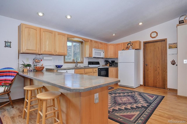 kitchen featuring white appliances, a kitchen bar, kitchen peninsula, and light wood-type flooring