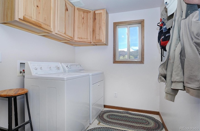 clothes washing area featuring cabinets, light tile patterned floors, and washing machine and clothes dryer