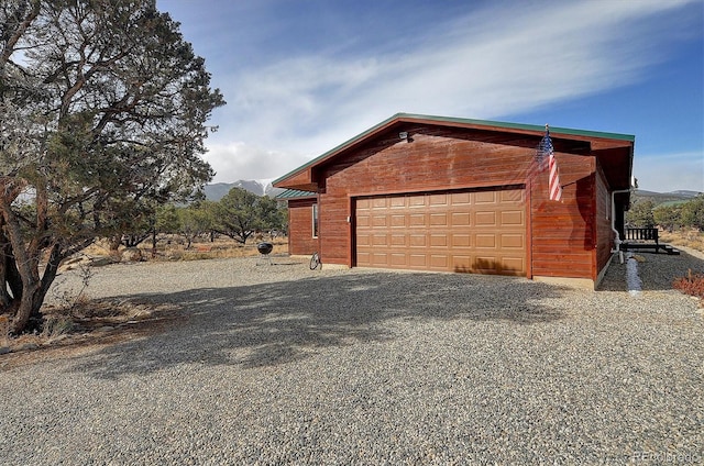 view of side of home with a garage, a mountain view, and an outdoor structure