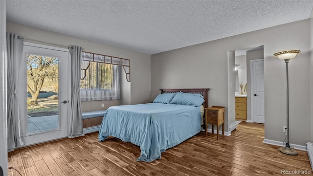 bedroom with hardwood / wood-style floors, access to outside, a textured ceiling, and baseboard heating