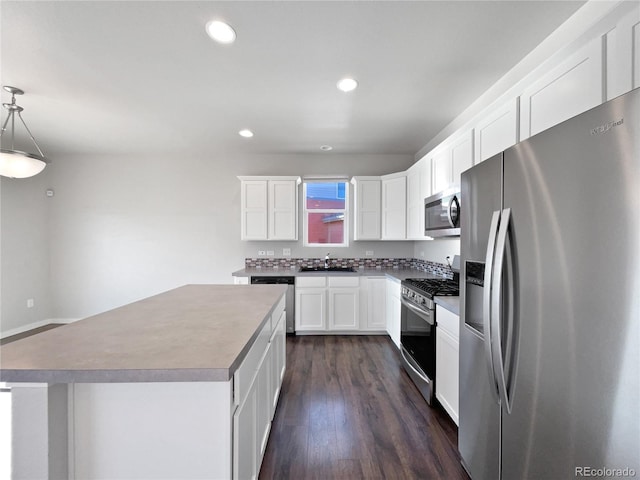 kitchen with white cabinets, appliances with stainless steel finishes, a center island, sink, and hanging light fixtures