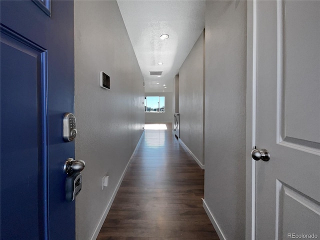 corridor with a textured ceiling and dark hardwood / wood-style floors