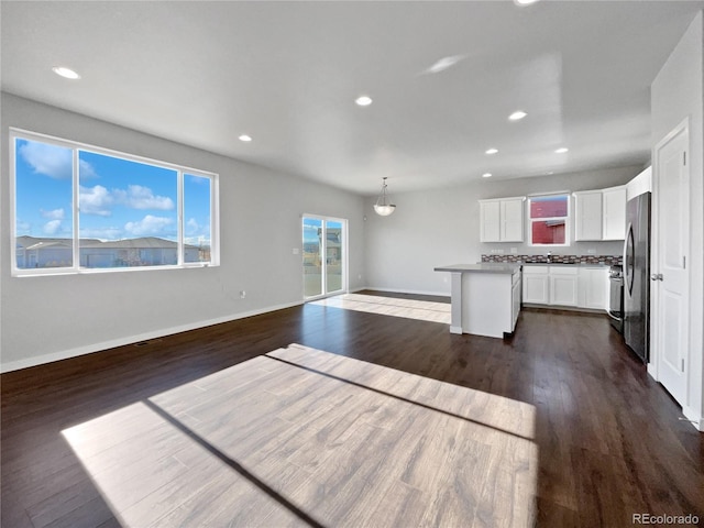 kitchen with pendant lighting, a center island, white cabinetry, decorative backsplash, and stainless steel refrigerator