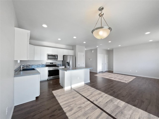 kitchen featuring appliances with stainless steel finishes, a center island, pendant lighting, white cabinets, and sink