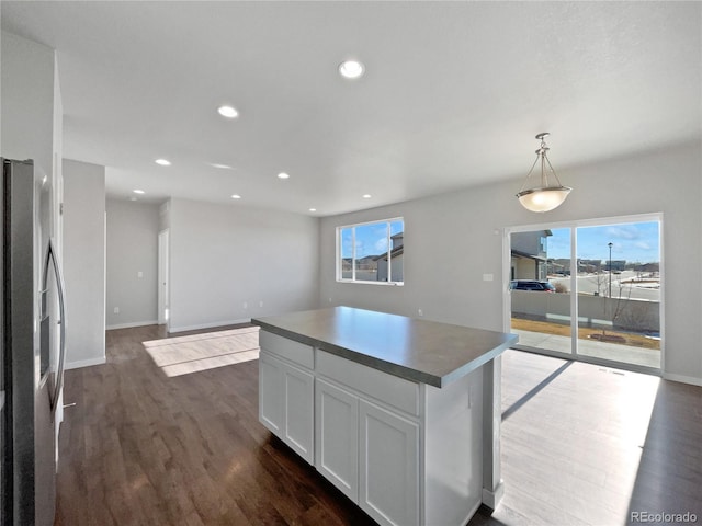 kitchen featuring decorative light fixtures, a center island, dark wood-type flooring, white cabinets, and stainless steel fridge