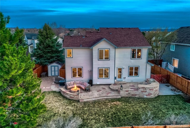 back of house featuring a patio area, a fenced backyard, a storage unit, and an outbuilding