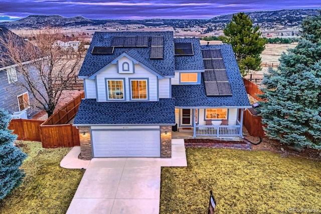 traditional home featuring driveway, roof with shingles, covered porch, fence, and a mountain view