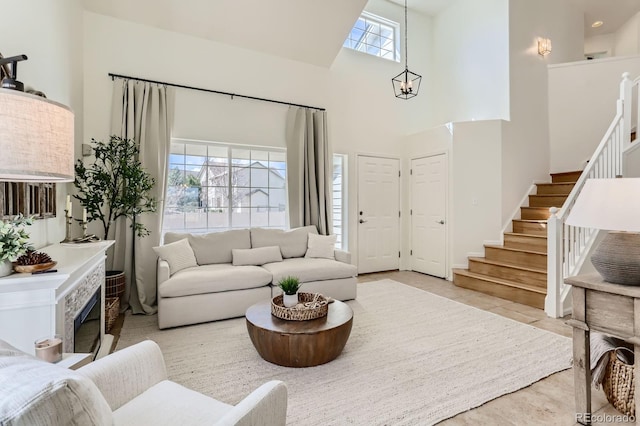 living area featuring stairs, a high ceiling, light tile patterned floors, and a notable chandelier