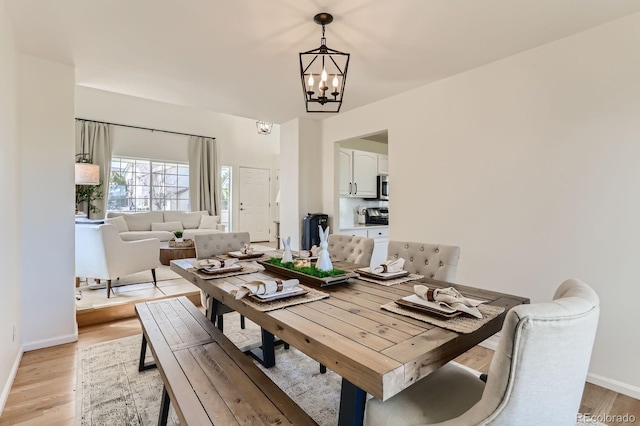 dining area with an inviting chandelier, light wood-style flooring, and baseboards