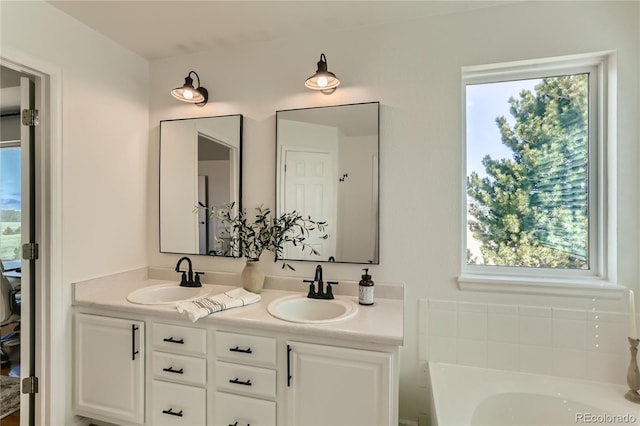 full bathroom featuring double vanity, a sink, and a healthy amount of sunlight