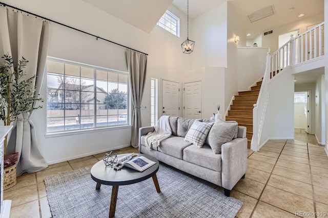 living area with stairs, visible vents, a towering ceiling, and baseboards