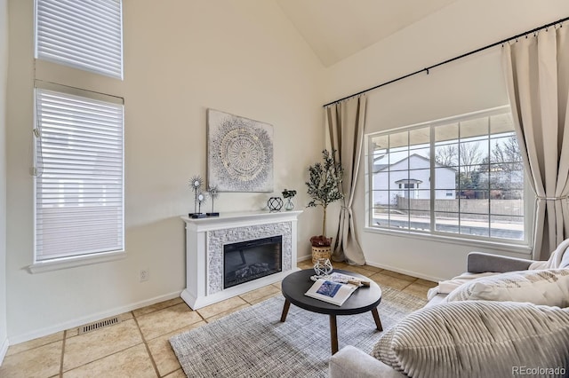 living room featuring high vaulted ceiling, a fireplace, visible vents, baseboards, and tile patterned floors