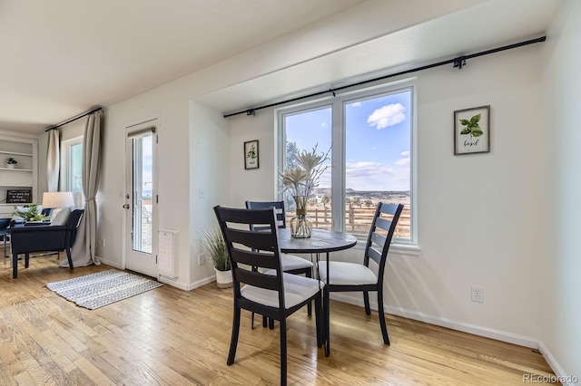 dining space with light wood-style flooring and baseboards