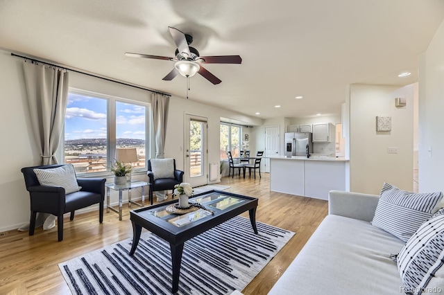 living room featuring recessed lighting, baseboards, ceiling fan, and light wood finished floors