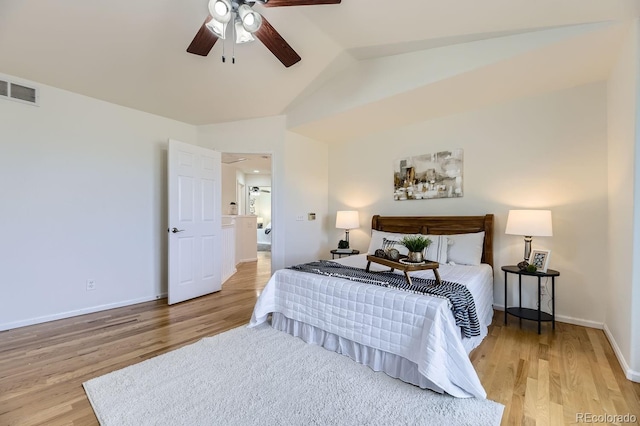 bedroom with light wood finished floors, baseboards, visible vents, and vaulted ceiling