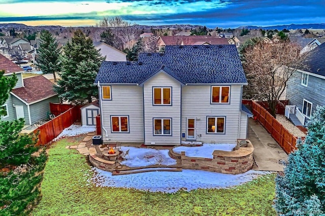 back of house featuring a storage unit, a patio, an outdoor fire pit, and a fenced backyard