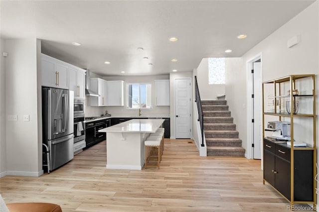 kitchen with white cabinetry, a center island, light hardwood / wood-style flooring, appliances with stainless steel finishes, and a kitchen breakfast bar