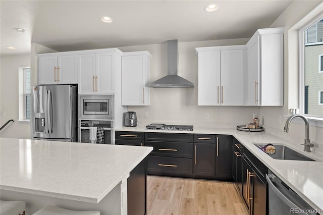 kitchen featuring stainless steel appliances, white cabinetry, sink, and wall chimney exhaust hood