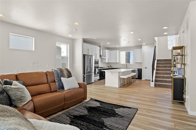 living room featuring plenty of natural light, recessed lighting, light wood-style floors, and stairway