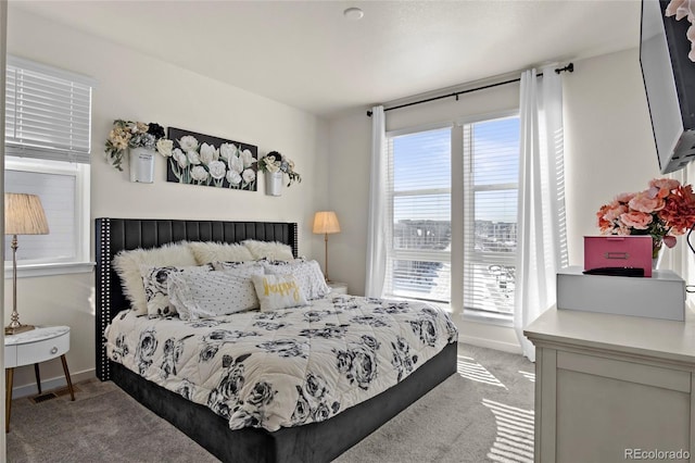 bedroom with baseboards, light carpet, and multiple windows